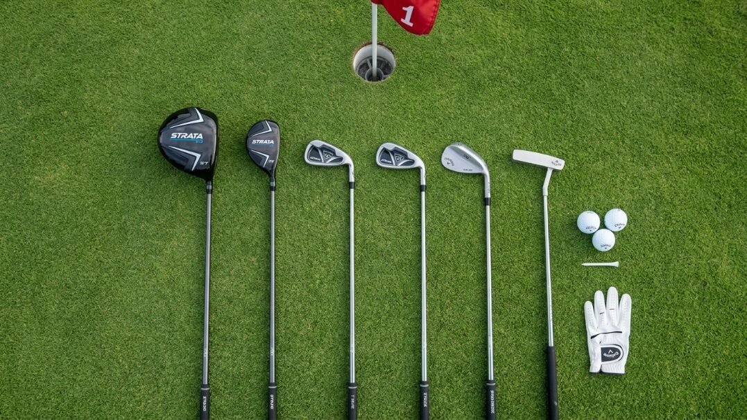 Top-down view of golf clubs, balls, and a glove laid out on green grass near a hole with flag number one.